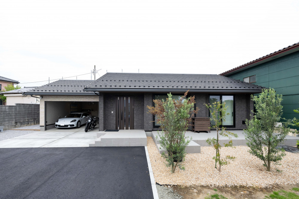 建物の凹凸を活かしてライトグレーとダークグレーのタイルを貼り分けた邸宅感あるファサード。タイルの質感が重厚感を演出し、大屋根の水平ラインが美しい外観です。