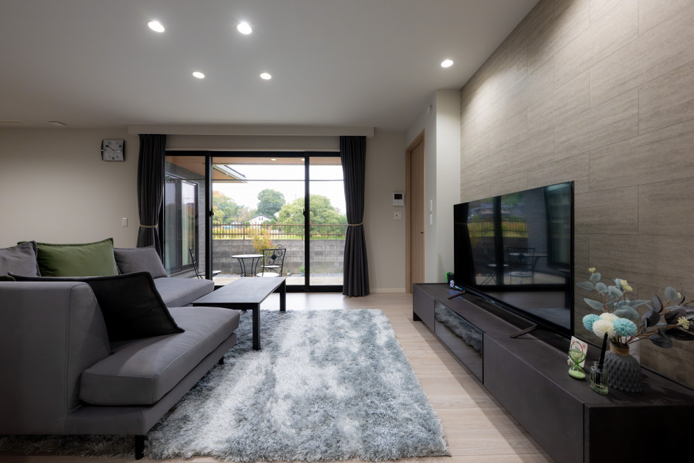 照明はダウンライトでスッキリとまとめ、リビングは調光にすることで時間帯に合わせた心地よさを演出。テレビボードの背面には石目調のアクセントクロスを施し、ラグジュアリー感をプラス。