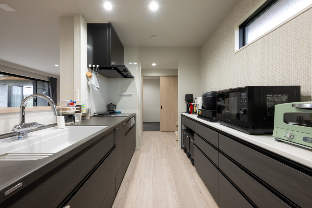 キッチンの背面に設置した幅2500mmのカウンター収納は、家電がすべて並べられるよう計画。見た目も使い勝手も両立しました。