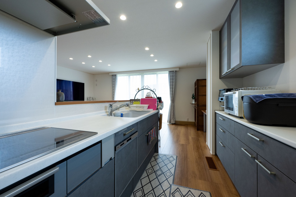 キッチンは対面キッチンで料理をしながらリビングのテレビも見ることができる配置。家電カウンターと吊戸棚で収納量も確保しています。